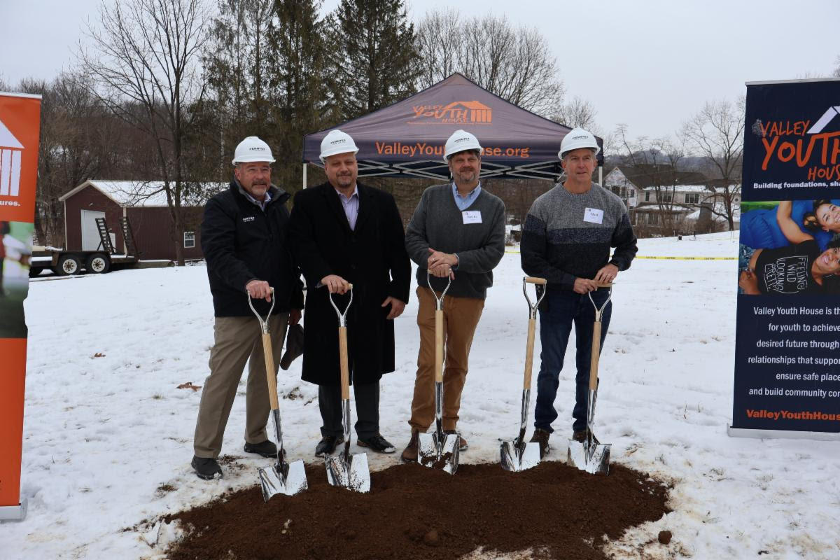 A group of men wearing hard hats holding shovels in the snow Description automatically generated