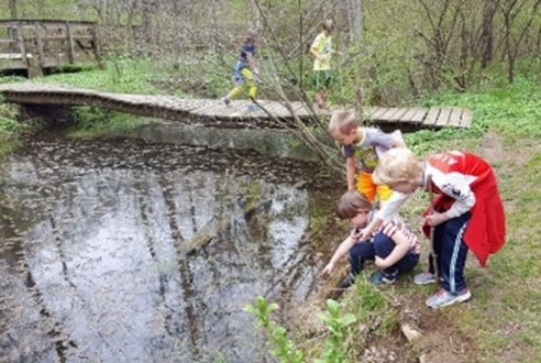 A group of children playing near a pond

Description automatically generated