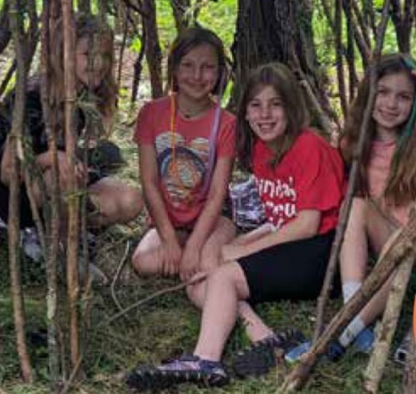 A group of girls sitting in a forest Description automatically generated