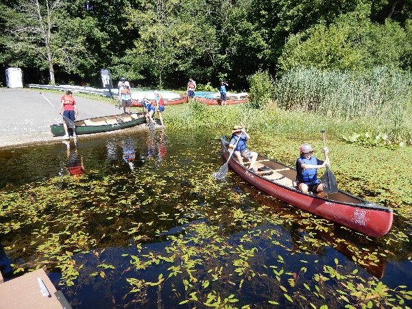 A group of people in canoes on a river Description automatically generated