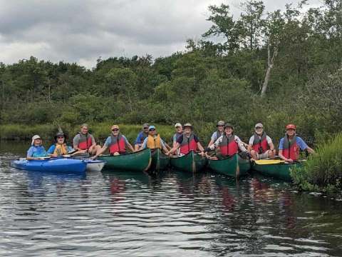 A group of people in canoes on a river Description automatically generated