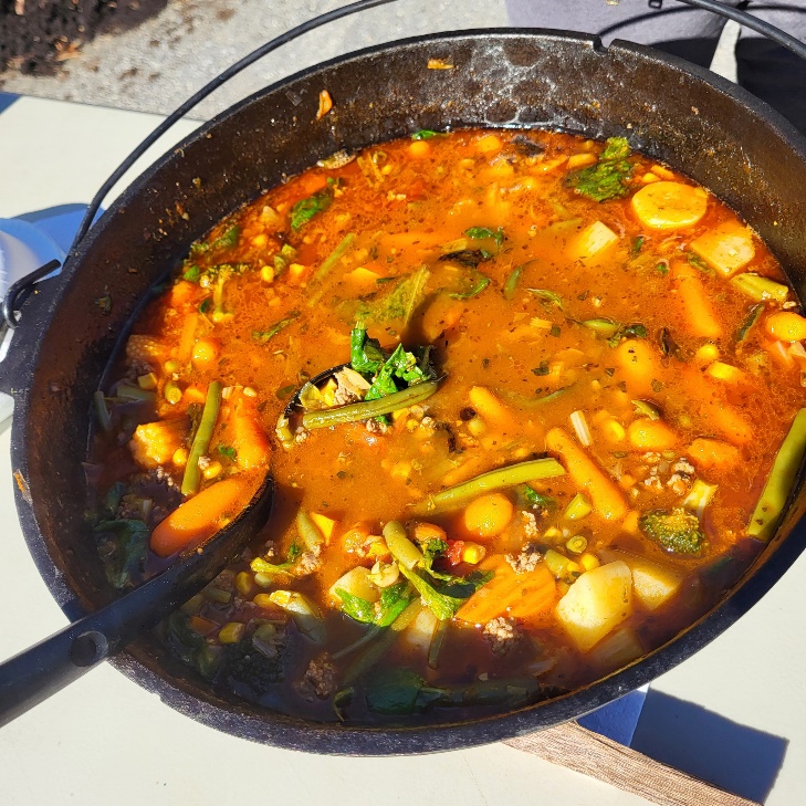 A pot of soup with a ladle

Description automatically generated